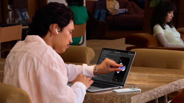 使用者坐在咖啡廳,用手指直接點 MacBook Pro 螢幕上的 app 畫面
