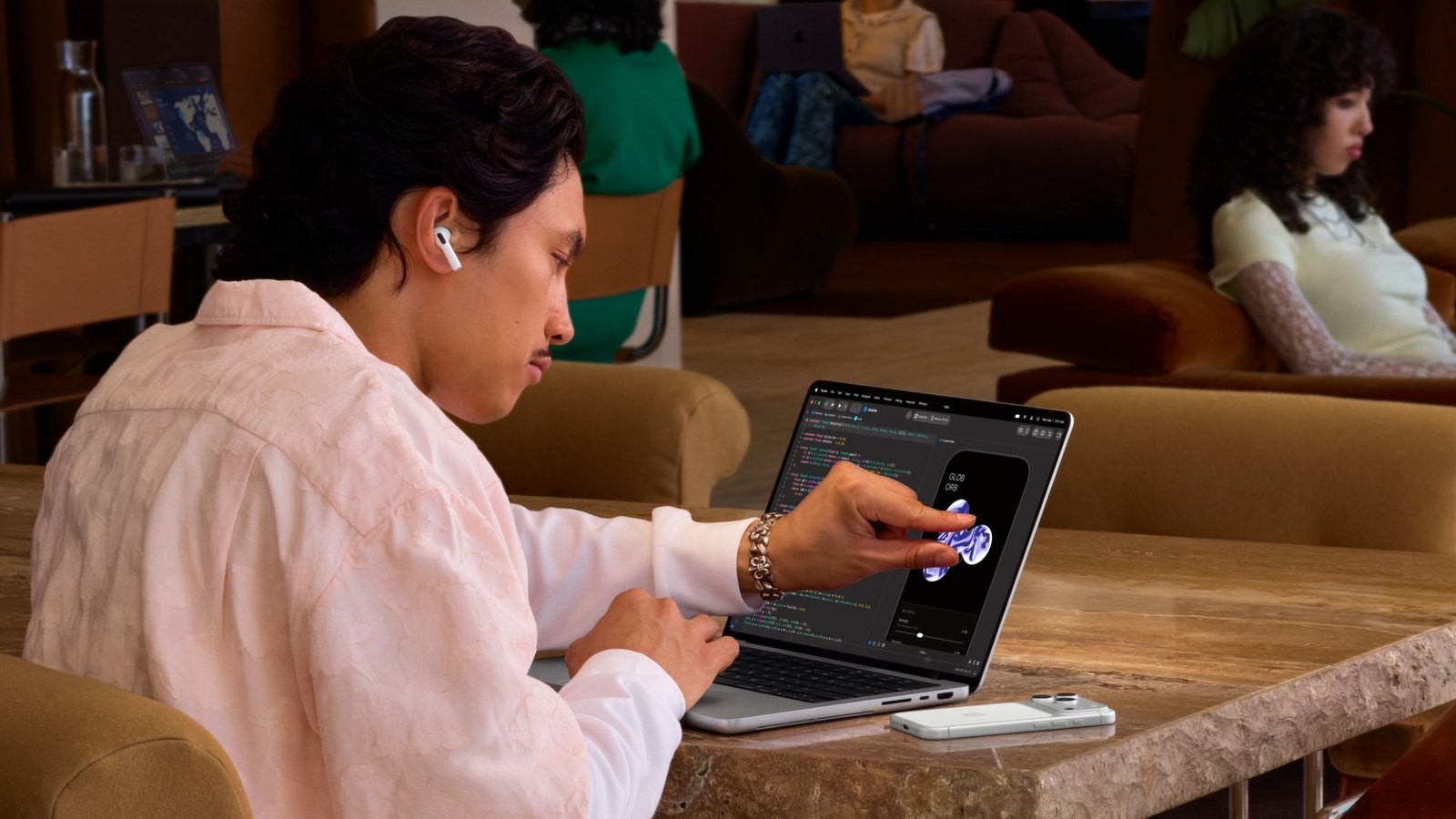 使用者坐在咖啡廳,用手指直接點 MacBook Pro 螢幕上的 app 畫面